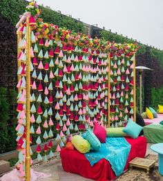 a bed covered in lots of colorful pillows next to a wall with many different colored decorations