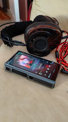 a cell phone sitting on top of a bed next to headphones