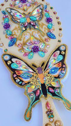 a butterfly shaped object with lots of colorful jewels on it's wings and back