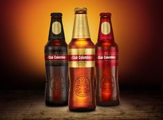 three bottles of beer sitting on top of a wooden table in front of an orange background