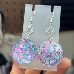 a pair of pink and blue earrings sitting on top of a plastic holder