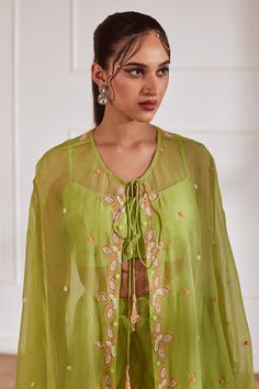 Green sheer cape with cutdana embellished floral motifs. Comes with crop top and sharara.
Components: 3
Pattern: Embroidered
Type Of Work: Cutdana,Sequin,Pearl
Neckline: Cape: Tie-up, Crop top: U-neck
Sleeve Type: Cape: Cape sleeves, Crop top: Sleeveless
Fabric: Semi Raw Silk, Georgette, Viscose Organza, Lining: Shantoon
Color: Green
Other Details: 
Attached lining
Closure:
Cape: Front drawstring
Crop Top: Back hook
Sharara: Side zip
Occasion: Cocktail,Sangeet - Aza Fashions Semi-stitched Tops With Dupatta For Festive Occasions, Wedding Tops With Dupatta For Eid, Designer Green Chinon Blouse, Bohemian Cutdana Tops For Festive Season, Wedding Tops With Dupatta For Navratri, Wedding Tops With Dupatta For Diwali, Festive Green Chinon Blouse, Bohemian Georgette Festive Sets, Designer Pista Green Blouse With Dupatta