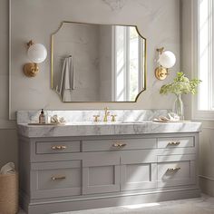 an elegant bathroom with marble counter tops and gold accents on the mirror above the sink