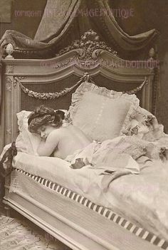 an old black and white photo of a woman laying in bed with her head on the pillow