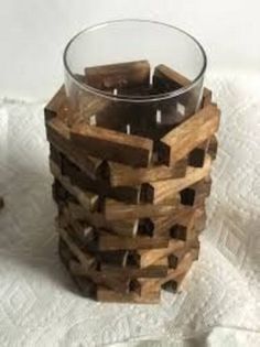 a candle holder made out of wooden blocks on a white tablecloth with a glass