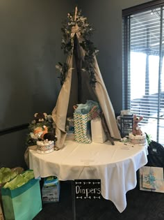 a teepee tent is set up on a table with presents and other items around it