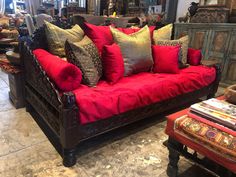 a living room filled with lots of red and gold pillows on top of a couch