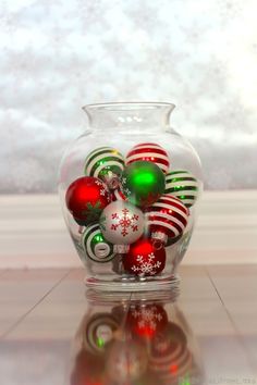 a glass vase filled with christmas ornaments on top of a tiled floor next to a window