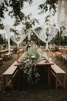 a long wooden table topped with flowers and greenery