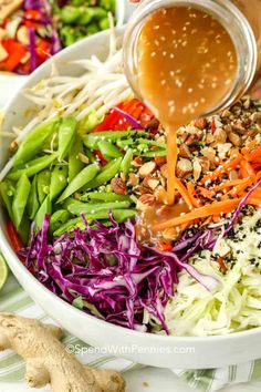 someone pouring dressing onto a colorful salad in a bowl