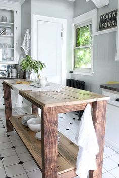 a kitchen island made out of wooden planks in the middle of a tiled floor