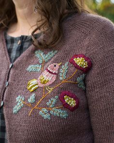 a close up of a person wearing a sweater with flowers on it and an owl