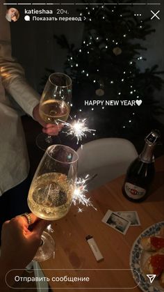 two people toasting wine glasses with sparklers in front of a christmas tree and holiday decorations