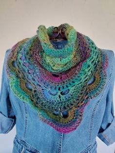 a blue jean jacket with a multicolored knitted scarf on top of it