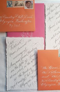 three envelopes with calligraphy on them, one is orange and the other is pink