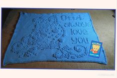 a blue crocheted blanket with a bear on it