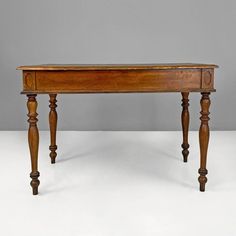 an old wooden table with two legs and a drawer on one end, against a gray background