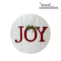 the word joy written in red painted on a white wooden sign with holly and bow