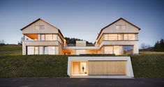 two large white houses sitting next to each other on top of a lush green hillside