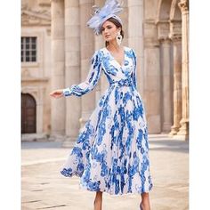 a woman in a blue and white dress is standing on the street with her hands out