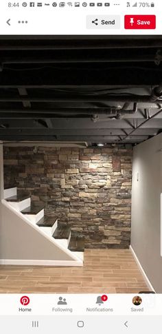 an empty room with stone walls and stairs in the center is seen from across the room