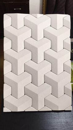 a close up of a wall made out of white bricks on a table with a vase in the background