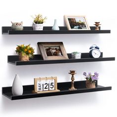 two black shelves with pictures and other items on them, one shelf has an alarm clock