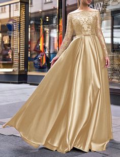 a woman in a gold dress is walking down the street