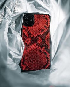 an iphone case with red and black snakeskin print on it, sitting in a plastic bag