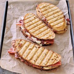 two grilled sandwiches sitting on top of wax paper