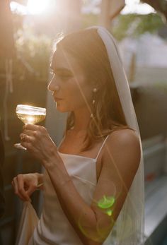 a woman in a wedding dress holding a glass of wine