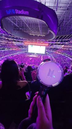 a person holding a microphone in front of a large crowd at a concert or show