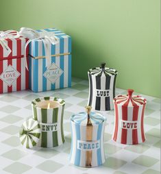 four colorful striped boxes sitting on top of a checkered tablecloth covered floor next to a green wall