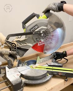 a person using a circular saw to cut wood with a mitt and other tools