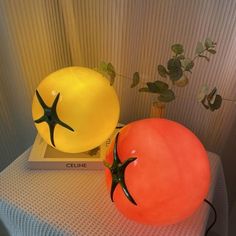 two large tomatoes sitting next to each other on top of a white table with a plant in the background