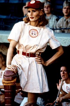 a woman in a baseball uniform standing next to a bat