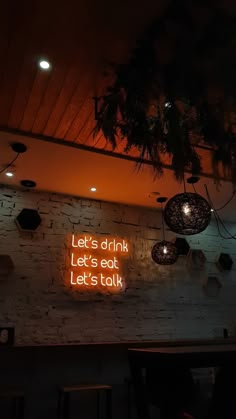 the neon sign on the wall says let's drink let's eat let's talk