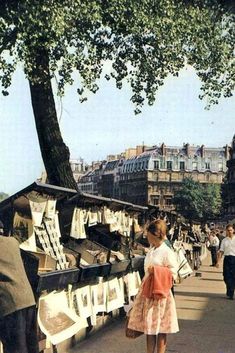 an old photo of a woman looking at clothes hanging on a line in the street