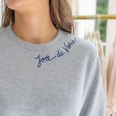 a woman wearing a grey shirt with blue writing on it