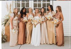 a group of women standing next to each other in front of a white building with flowers