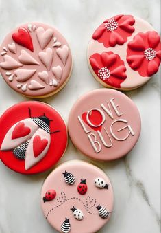 four decorated cookies sitting on top of a white counter next to red and black decorations