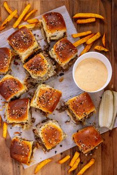 some food is laying out on a table next to french fries and dipping sauce in a bowl