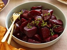 a bowl filled with sliced beets next to bread and other food on a table