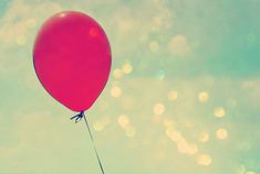 a red balloon floating in the air on a sunny day