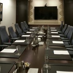 an empty conference room set up for a meeting with blue chairs and black table cloths