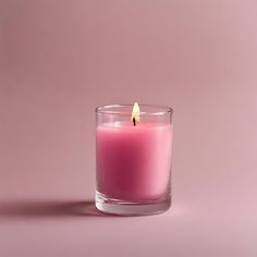 a pink candle in a glass on a pink background