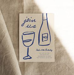 a wine bottle and glass are on the tablecloth with blue ink that says join us