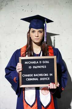 a woman in graduation cap and gown holding a sign