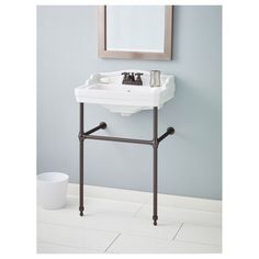 a white sink sitting under a mirror on top of a bathroom counter next to a trash can