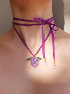 a woman wearing a purple necklace with flowers on the front and back of her neck